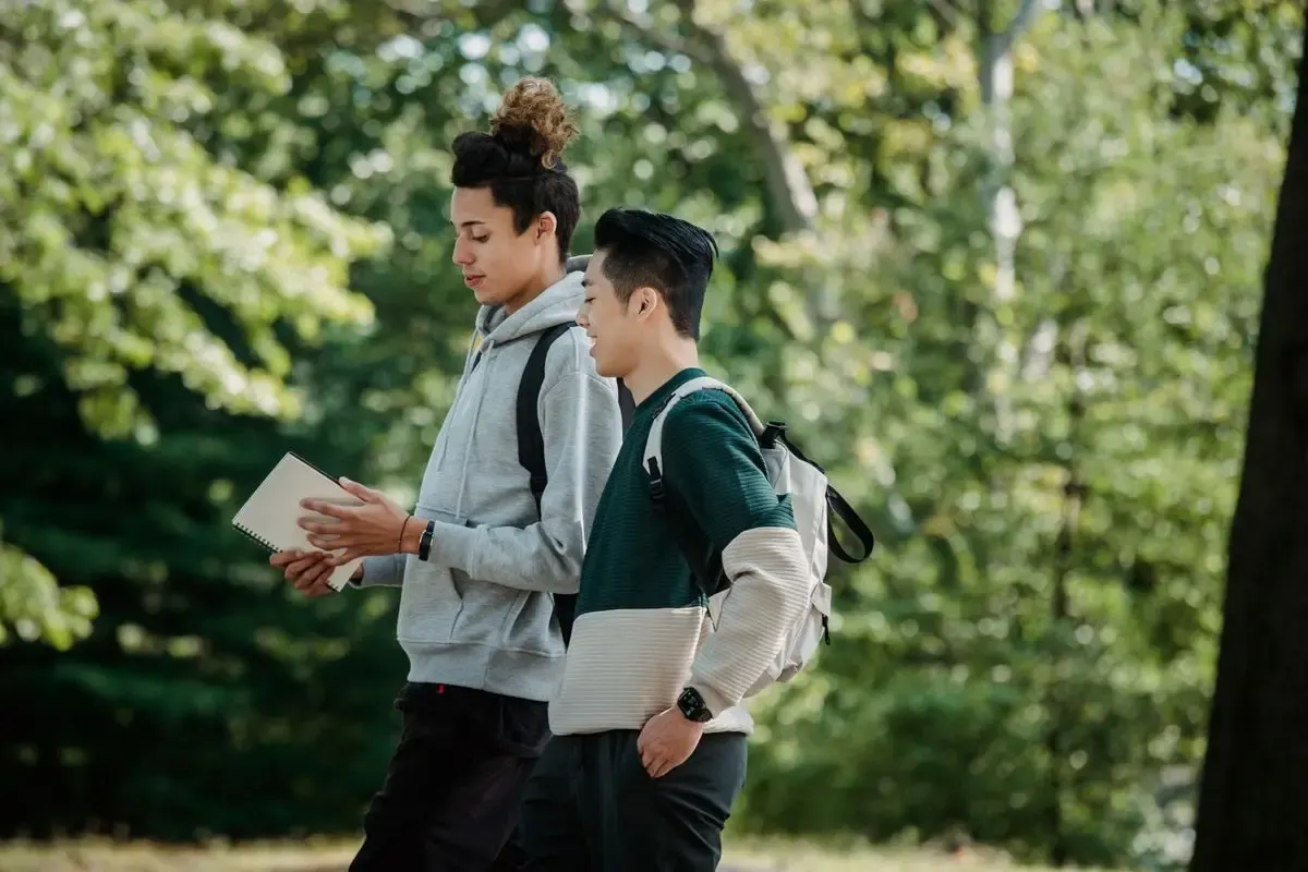 Two students walking across campus with their laptops
