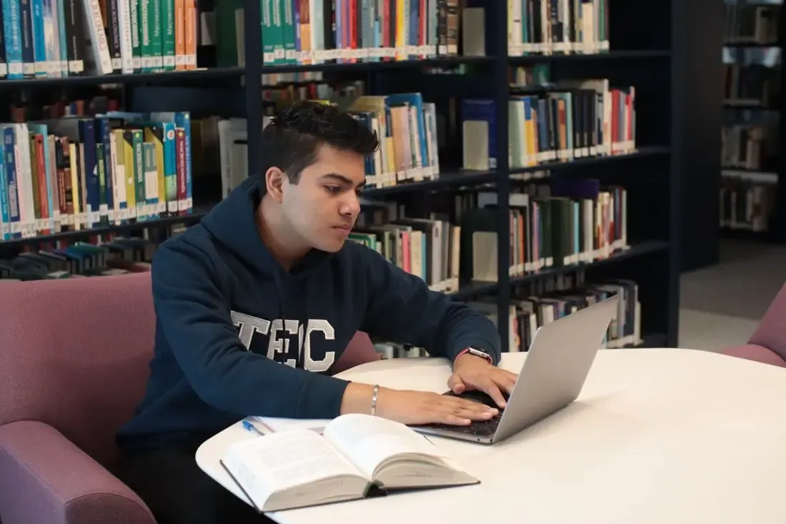 A student practising on a laptop in the library